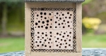 A bee house made of wooden blocks pre-drilled with various diameter tunnels and bamboo. 